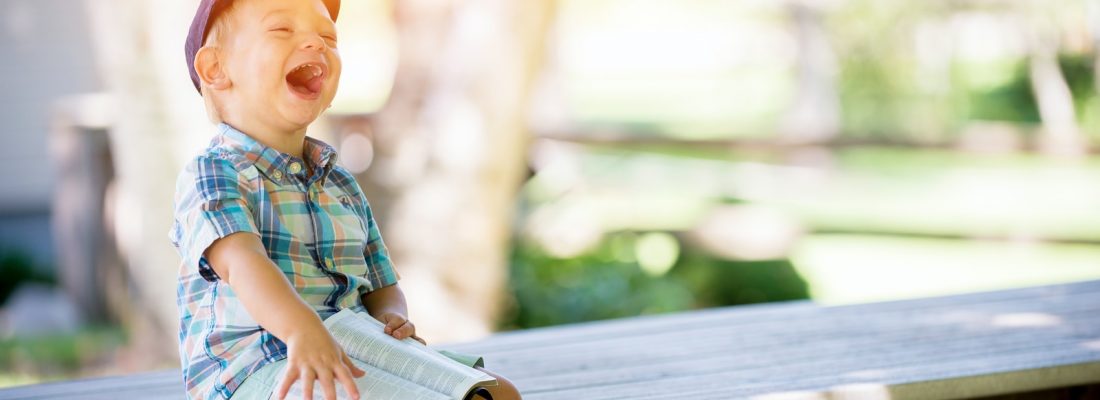 boy sitting on bench while holding a book